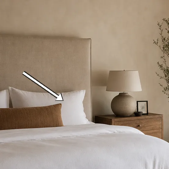 Close-up of the beige upholstered headboard and crisp white bedding.