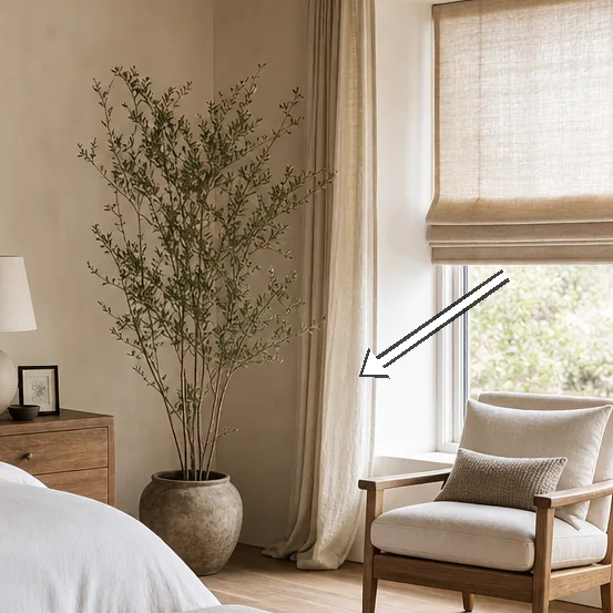Window nook with linen shade, chair, and potted plant nearby.