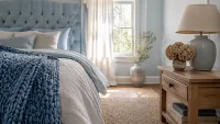 Wide establishing shot of the whole pale blue bedroom with tufted headboard.